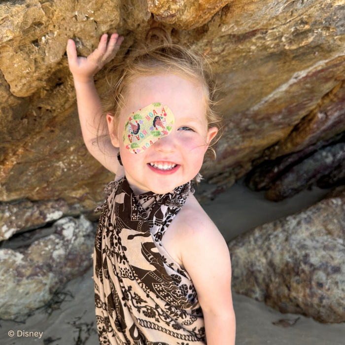 Smiling girl climbing rocks, wearing a Disney Moana eye patch