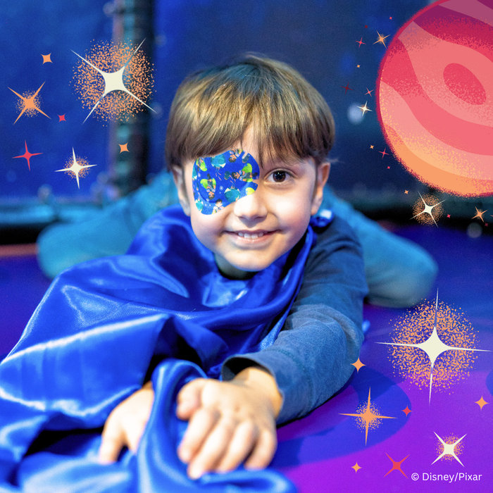 Boy in a cape on a space backdrop wearing an Elio eye patch