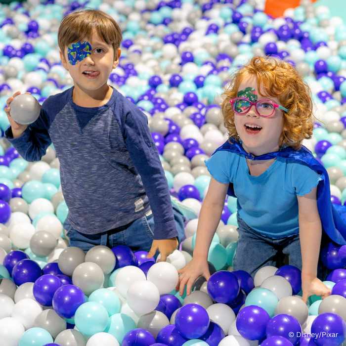 Two children in a ball pit wearing Disney and Pixar Elio eye patches