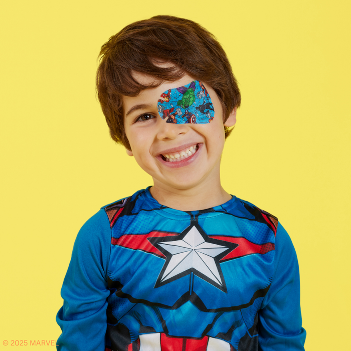 Smiling boy in a Captain America costume wearing a blue Avengers eye patch